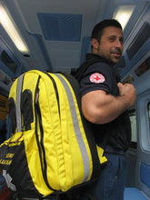 Cargar imagen en el visor de la galería, Imagen de la mochila profesional Mark Pro amarilla y negra transportada por un profesional sanitario
